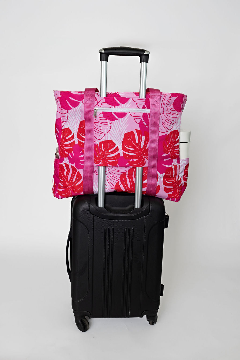 pink and red tropical solmate tote with trolley sleeve on carry on suitcase