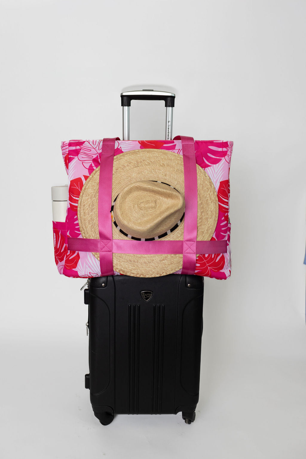 pink and red tropical solmate tote with straps to carry wide brim hat on carry on suitcase